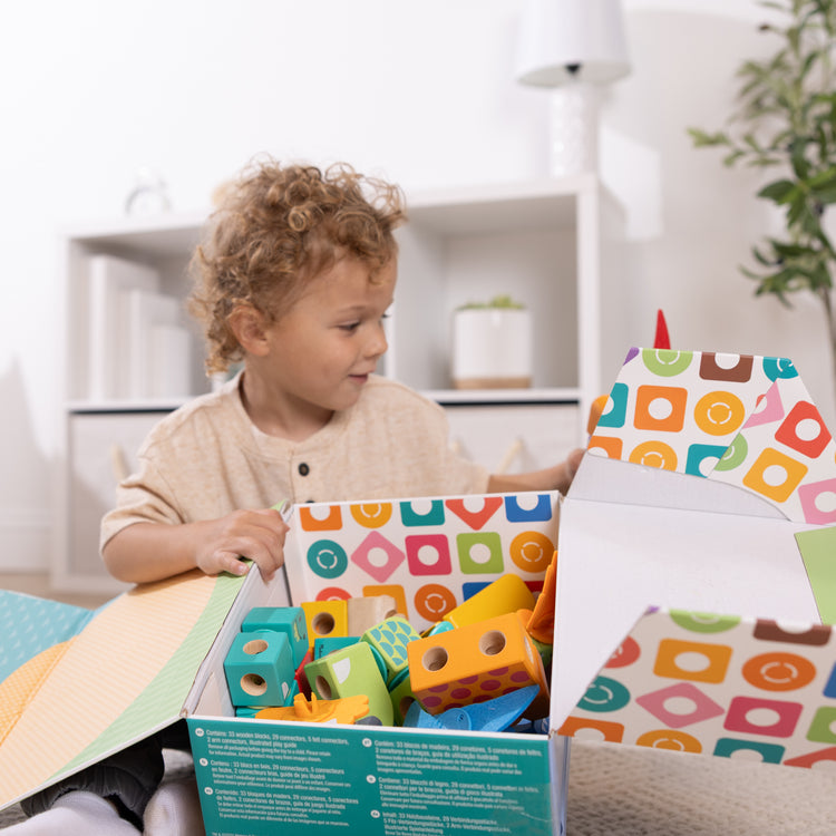 A kid playing with The Melissa & Doug Blockables™ Dinosaur Snap And Play, Mix And Match Connectable Wooden Building Blocks Play Set Toy for Preschool Boys And Girls (69 Pcs)