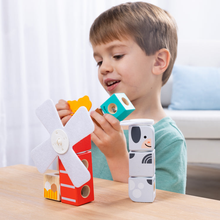 A kid playing with The Melissa & Doug Blockables™ Farm and Woodland 2-Pack Bundle Connectable Wooden Building Blocks Preschool Play Set Toy 