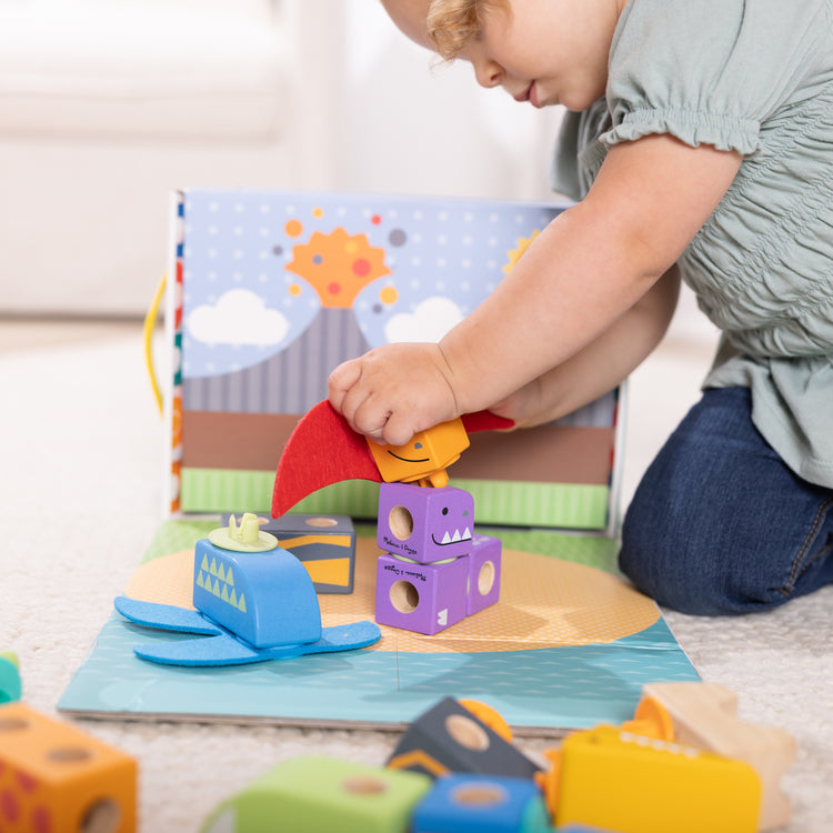 A kid playing with The Melissa & Doug Blockables™ Dinosaur Snap And Play, Mix And Match Connectable Wooden Building Blocks Play Set Toy for Preschool Boys And Girls (69 Pcs)