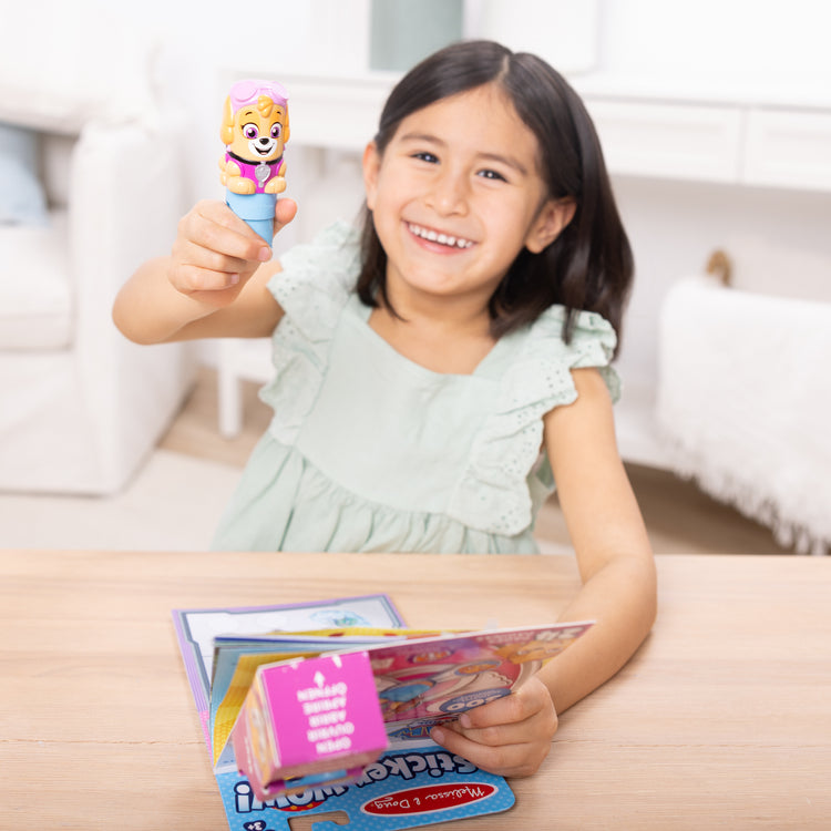 A kid playing with The Melissa & Doug Sticker WOW!™ PAW Patrol Skye Bundle: 24-Page Activity Pad, Sticker Stamper, 500 Stickers, Mini Pad, Arts and Crafts Fidget Toy Collectible Character