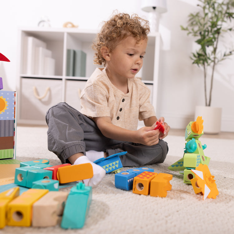 A kid playing with The Melissa & Doug Blockables™ Dinosaur Snap And Play, Mix And Match Connectable Wooden Building Blocks Play Set Toy for Preschool Boys And Girls (69 Pcs)