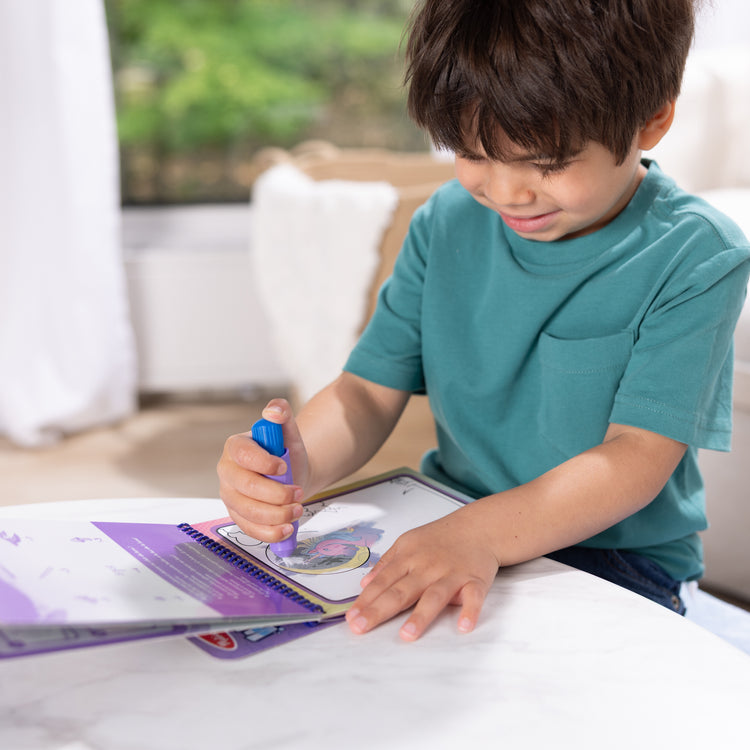 A kid playing with The Melissa & Doug Water WOW! Reusable Water-Reveal Coloring Activity Pad Travel Toy – Unicorn