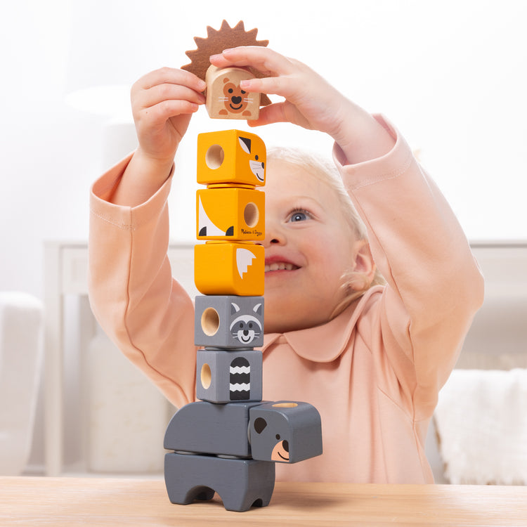 A kid playing with The Melissa & Doug Blockables™ Farm and Woodland 2-Pack Bundle Connectable Wooden Building Blocks Preschool Play Set Toy 