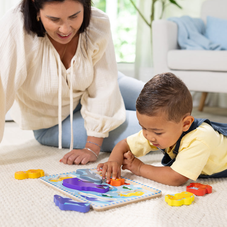 A kid playing with The Melissa & Doug Sea Creatures Ocean Wooden Chunky Puzzle - 7 Pieces