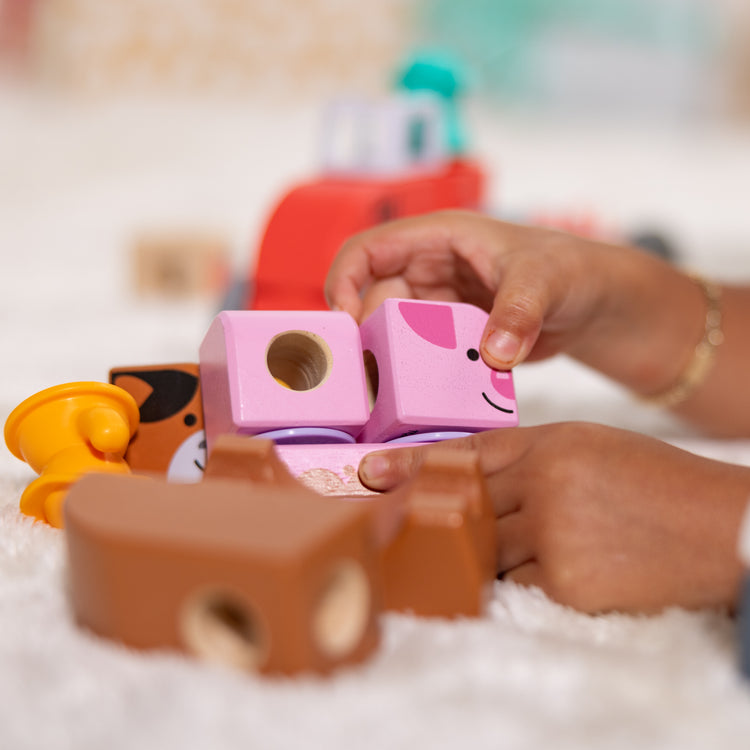 A kid playing with The Melissa & Doug Blockables™ Farm and Farm Friends 2-Pack Bundle Connectable Wooden Building Blocks Preschool Play Set Toy