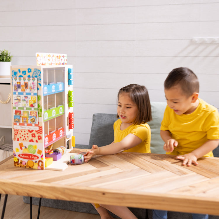 A kid playing with The Melissa & Doug Sort, Stock, Select Wooden Vending Machine Play Set, Wooden Toy Play Food For Boys and For Girls 3+