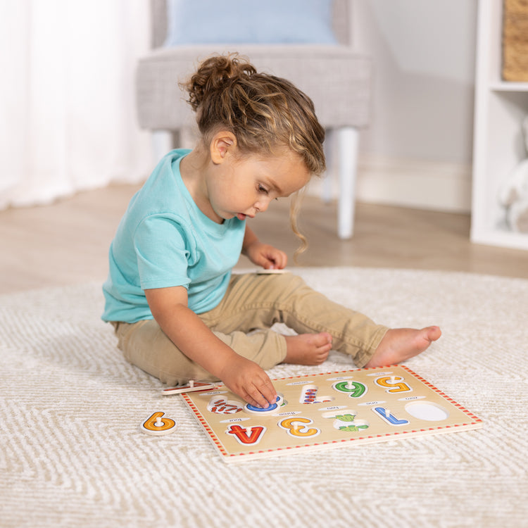 A kid playing with The Melissa & Doug Lift & See Numbers Wooden Peg Puzzle - 10 Pieces