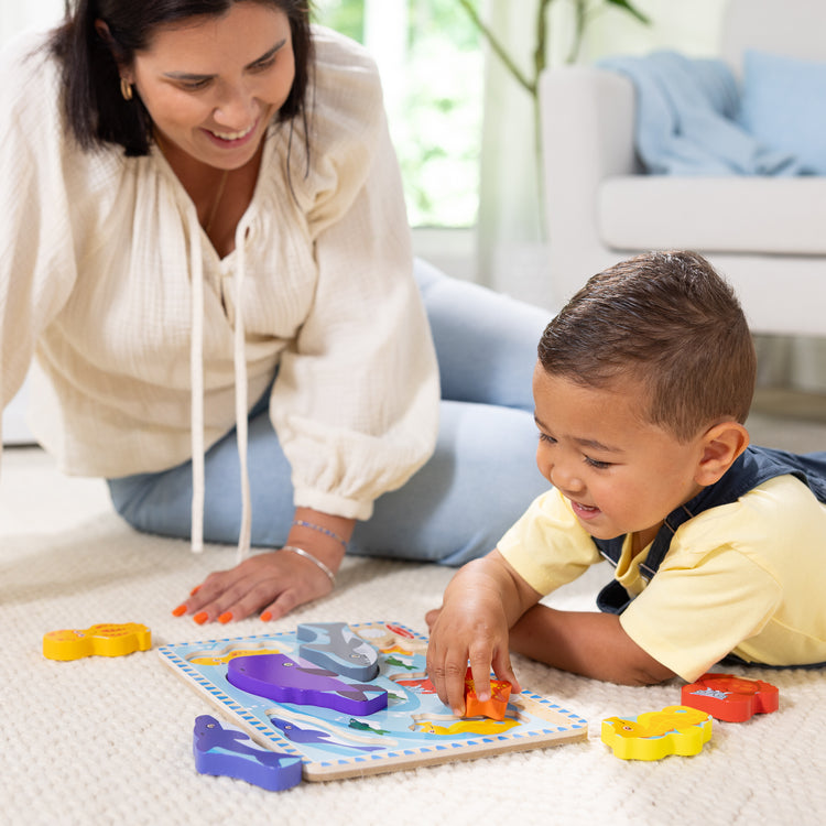A kid playing with The Melissa & Doug Sea Creatures Ocean Wooden Chunky Puzzle - 7 Pieces