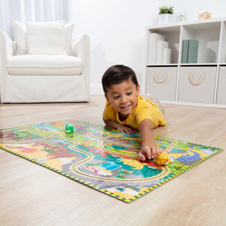 A kid playing with The Melissa & Doug Dinosaur Adventure Tracks Cardboard Jigsaw Floor Puzzle and 2 Wind-Up Dinos – 48 Pieces, for Boys and Girls 3+ 
