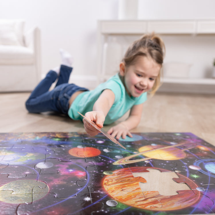 A kid playing with The Melissa & Doug Solar System Jumbo Floor Puzzle, 48-Piece Space-Themed Jigsaw Puzzle With Planet Guide, 3 x 2 Foot Kids Puzzles for Toddlers Ages 3+ (No Text on Puzzle)