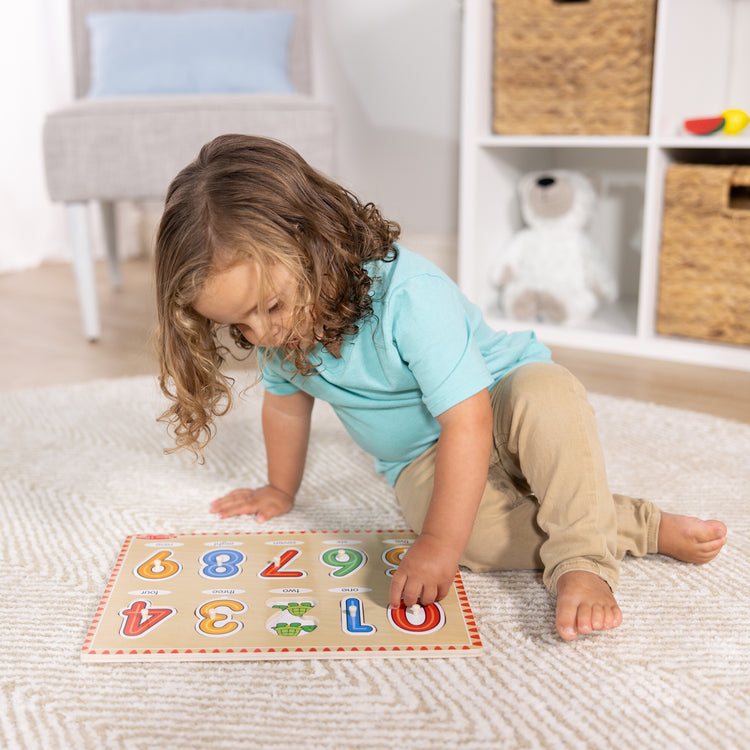 A kid playing with The Melissa & Doug Lift & See Numbers Wooden Peg Puzzle - 10 Pieces