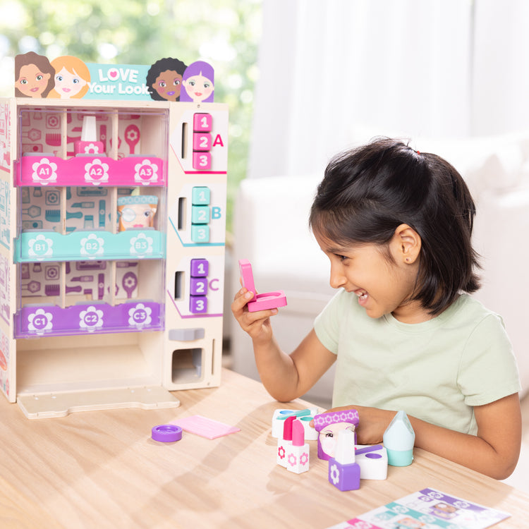 A kid playing with The Melissa & Doug Sort, Stock, Select Beauty Kiosk Vending Machine Play Set, Pretend Makeup Wooden Toy For Boys and For Girls 3+