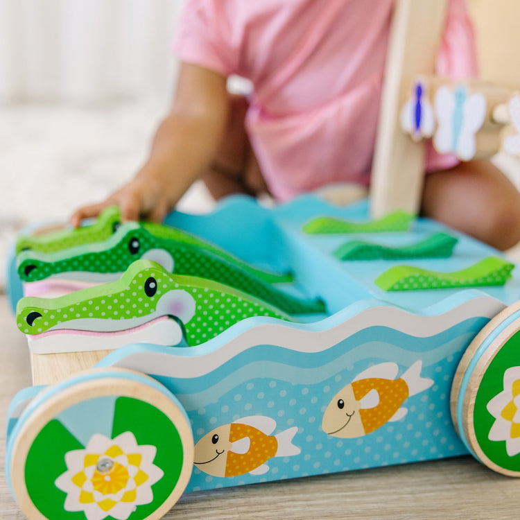 A kid playing with the Melissa & Doug First Play Chomp and Clack Alligator Wooden Push Toy and Activity Walker